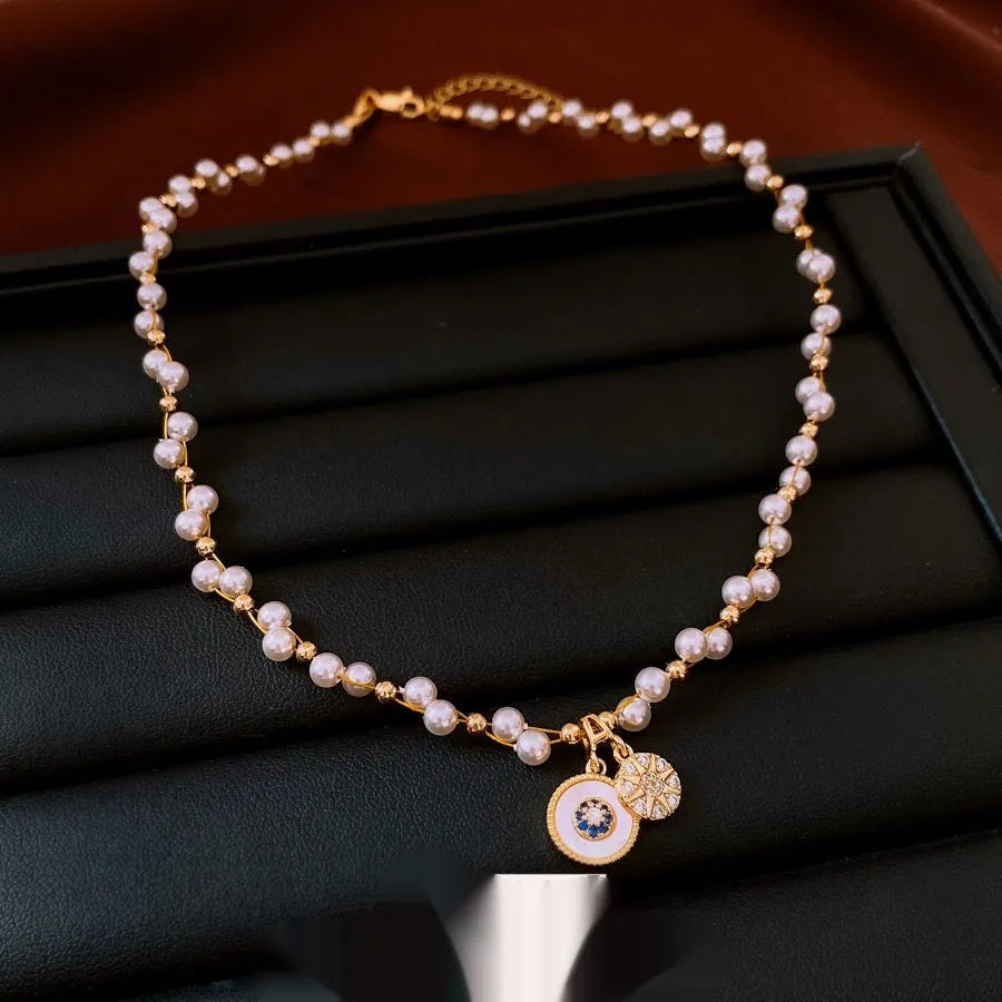 Gold electroplated women's necklace with round zircon and imitation pearl pendant on an adjustable clavicle chain.