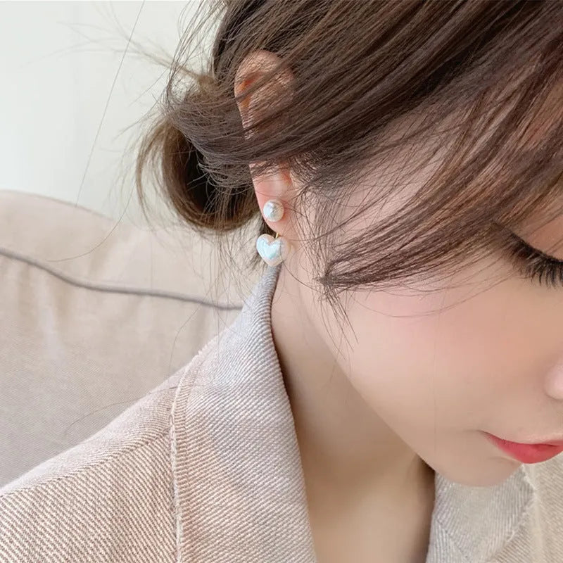 Close-up of a women's heart-shaped alloy stud earring with electroplated finish and central gemstone inlay.