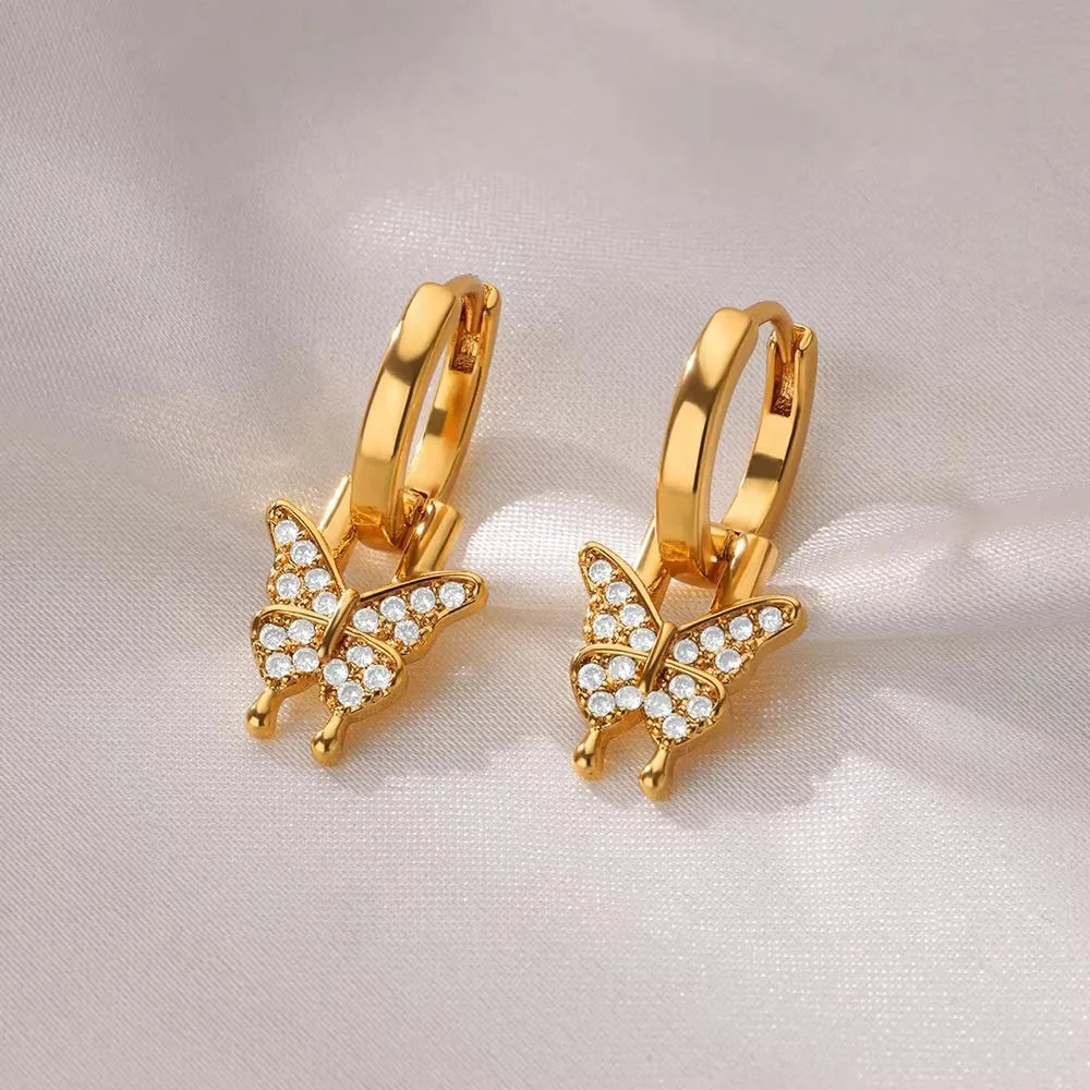 A pair of women's geometric butterfly earrings made from copper with heart, bow, and star shapes in a gold colour finish.