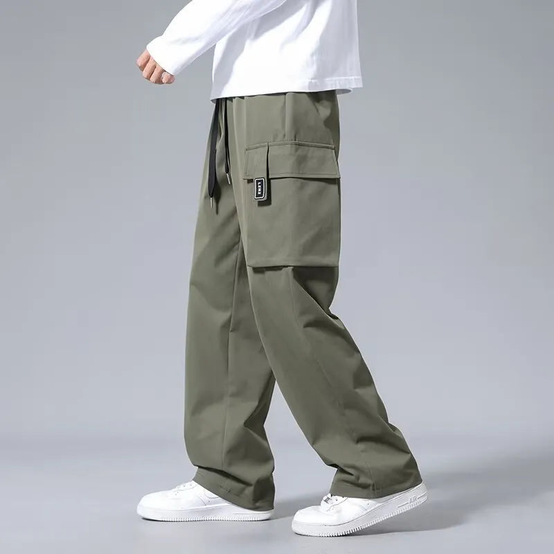 Boy wearing grey straight leg cargo pants with drawstring waist and large side pockets.