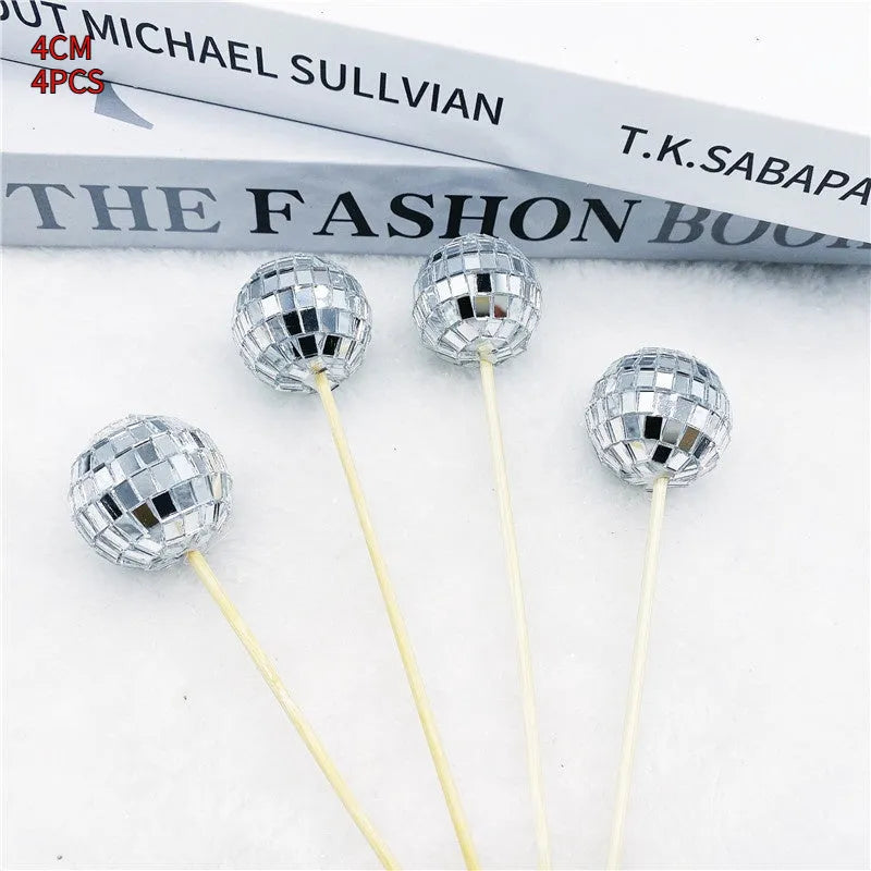 Glass disco ball cake decoration on wooden stick, showing reflective surface.