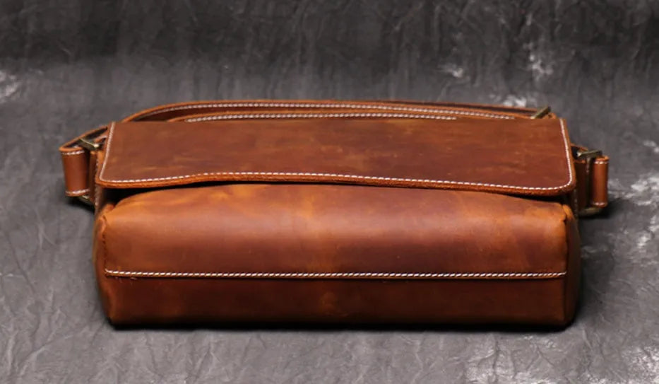 Vintage brown leather men's messenger bag with shoulder strap showing internal organiser pockets.