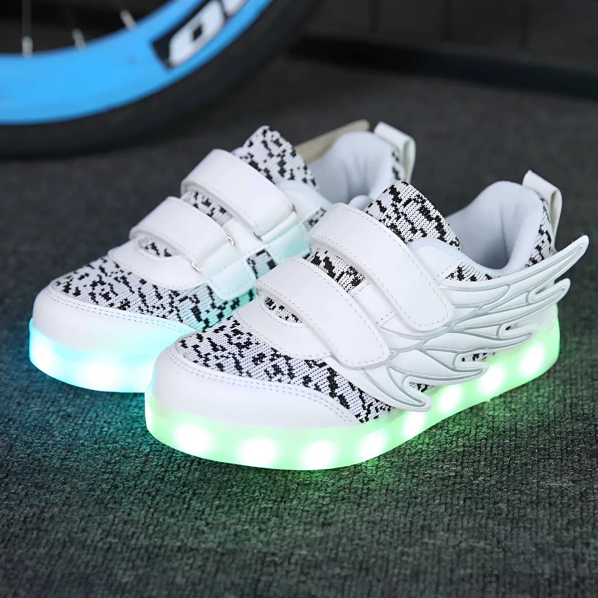 Children's plum red sneakers with colourful LED lights glowing in the soles.