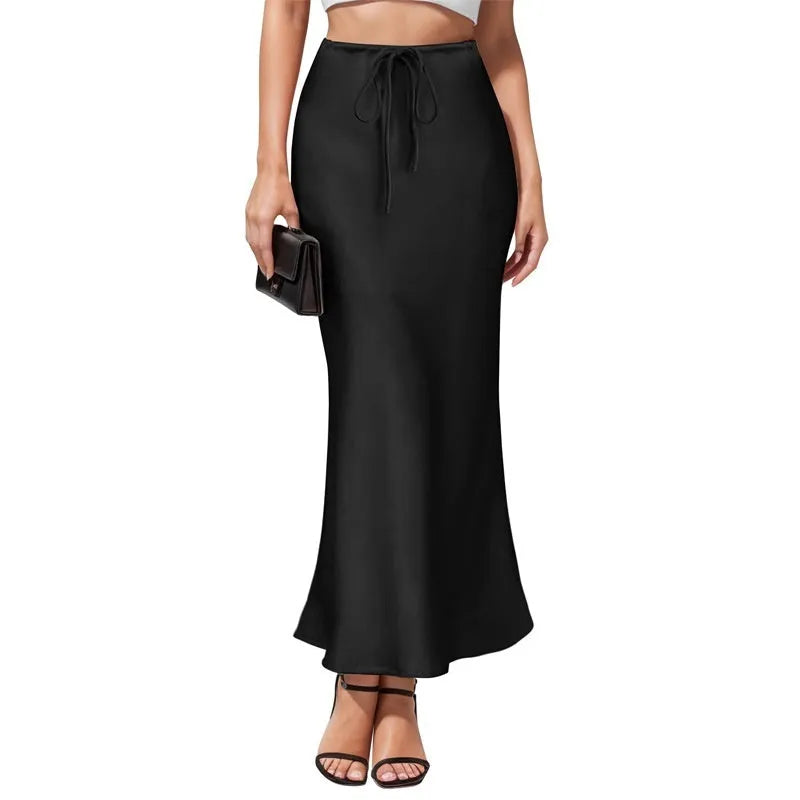 Women's high-waisted asymmetric satin skirt in black on a hanger, showing irregular hem detail.