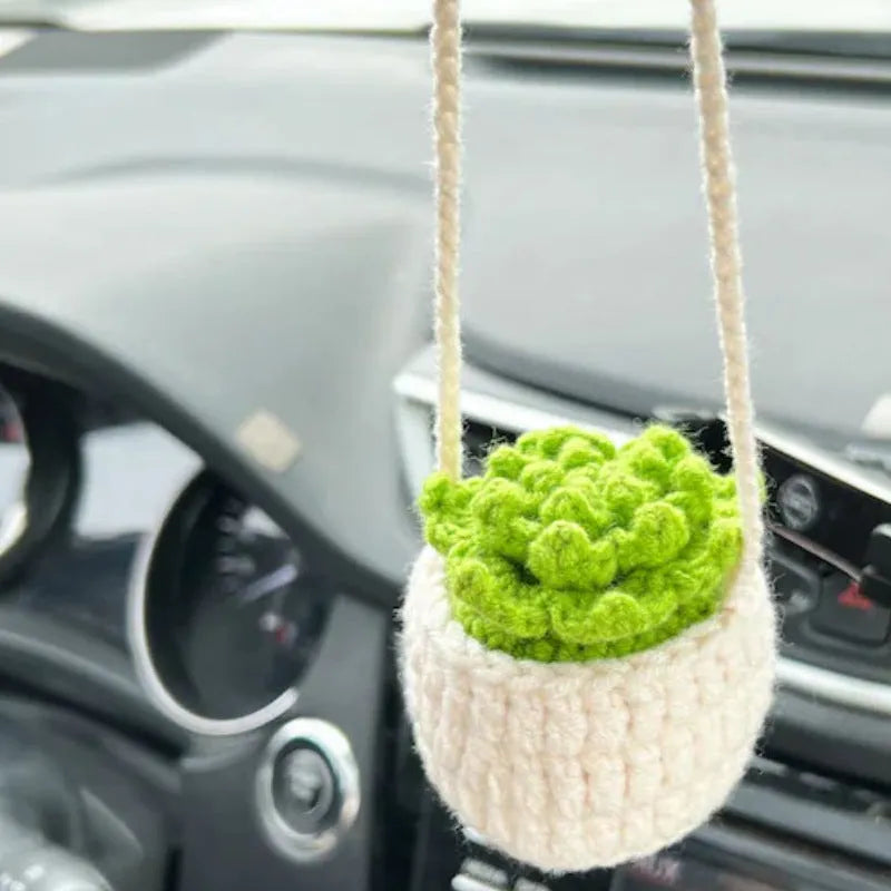 Green and white knitted wool car plant decoration basket with white hanging cord.