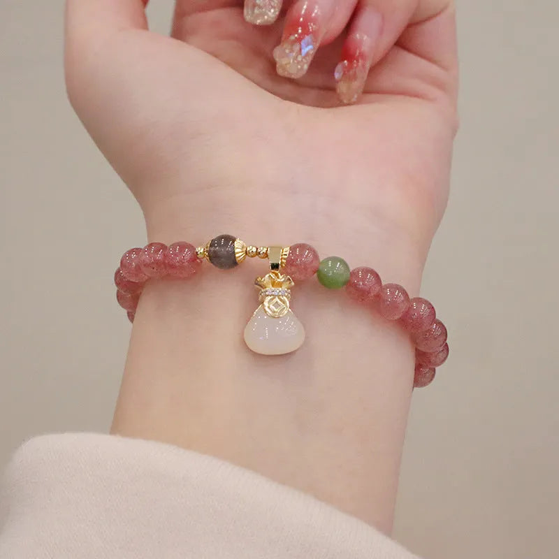 Women's strawberry quartz bracelet with geometric charm, purse charm, and safety buckle.