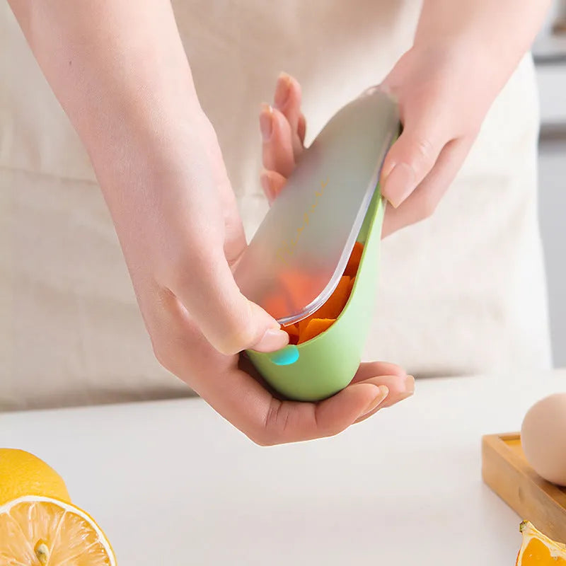Dark green vegetable peeler with a storage tube and stainless steel blade on a kitchen worktop.