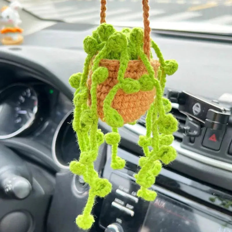 Green and white knitted wool car plant decoration basket with white hanging cord.