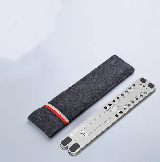 Aluminum alloy laptop stand in silver colour, folded to show its slim profile next to a 15-inch laptop.