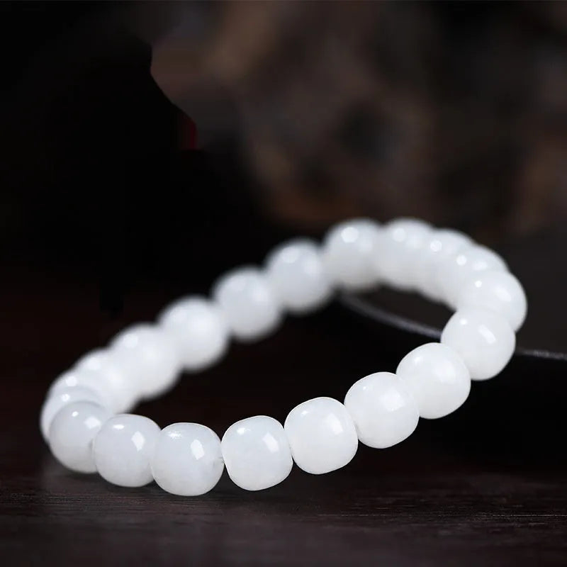 White Hetian jade barrel bead bracelet for men and women on a neutral background.