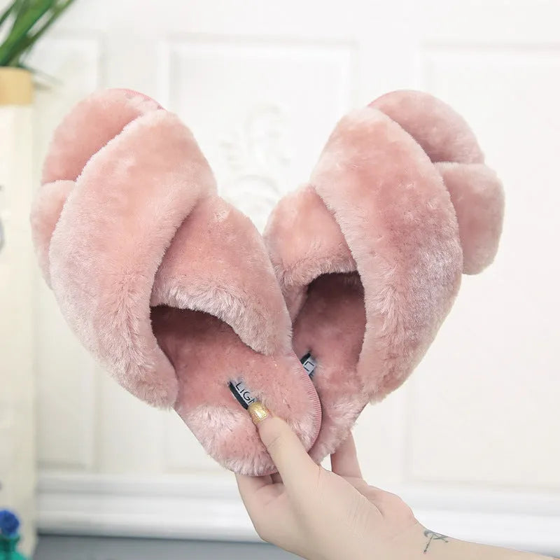 Women's black cross-strap open-toe fur slippers showing the patterned non-slip rubber sole.