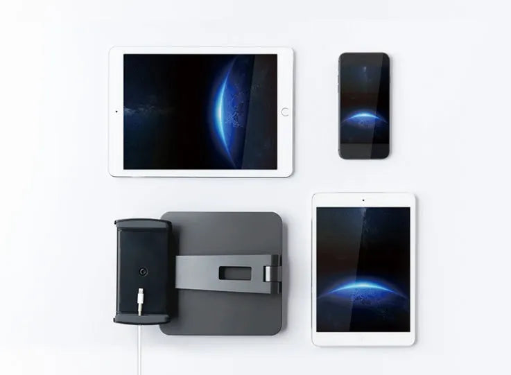 Silver foldable aluminium phone and tablet holder on a desk, showing 360-degree rotation feature.
