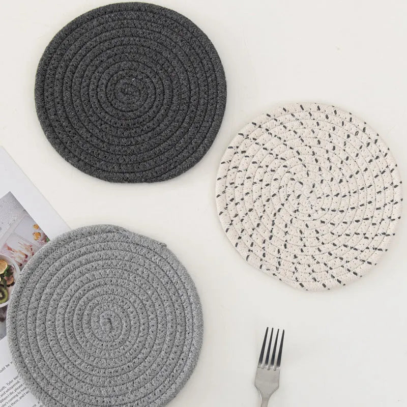 Set of three round cotton cord coasters in blue colour, 18cm diameter, on a table.