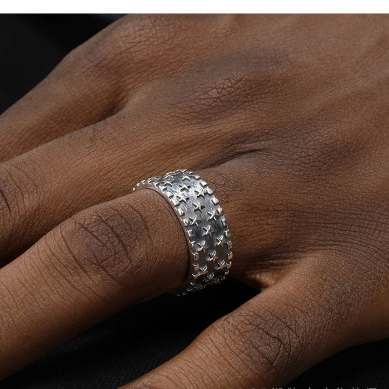 Adjustable sterling silver ring with a geometric pattern of five pointed stars on the band.