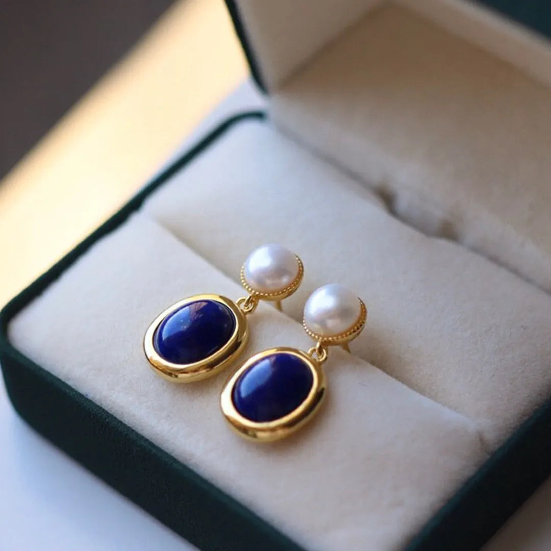 A pair of simple sterling silver earrings featuring blue lapis lazuli pearls and auspicious pattern detailing.