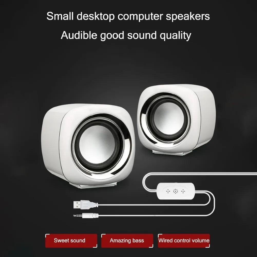 Pair of mini desktop speakers with 3.5mm audio plug on desk beside laptop