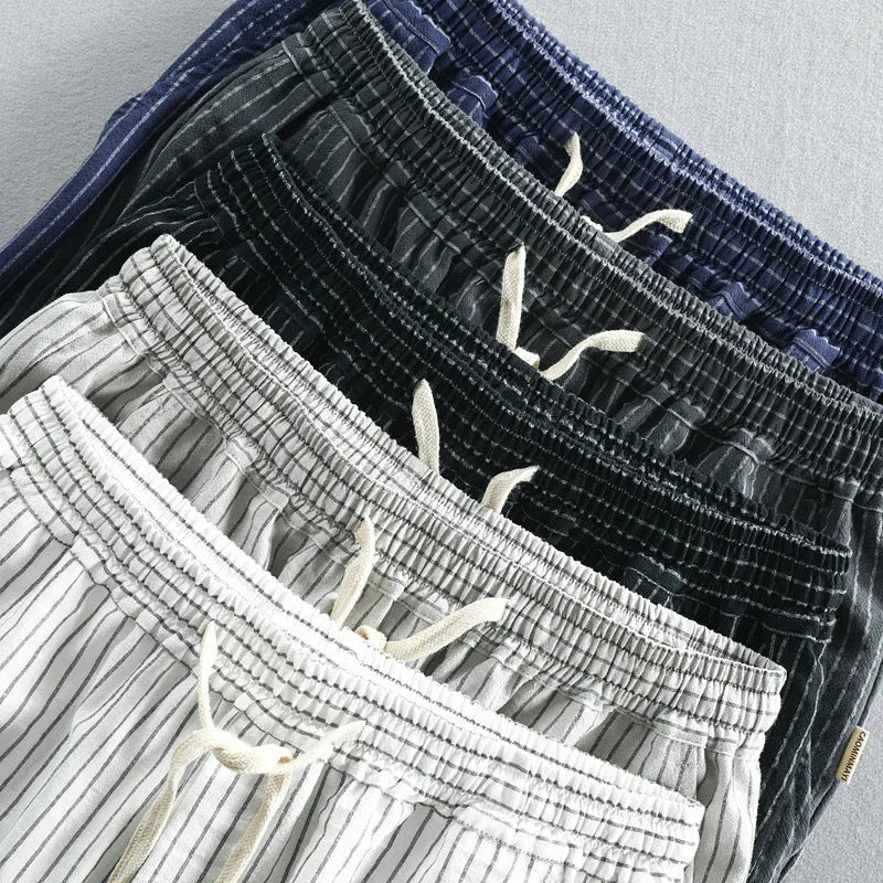 Man wearing black and white striped cotton casual shorts with a loose straight fit.