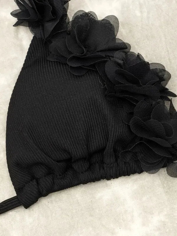 Black women's bikini set with gathered top and matching shorts laid flat.