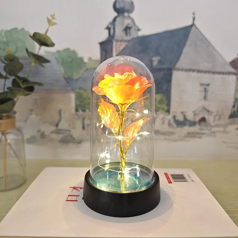 Small glass night lamp with plastic flowers on a black base.
