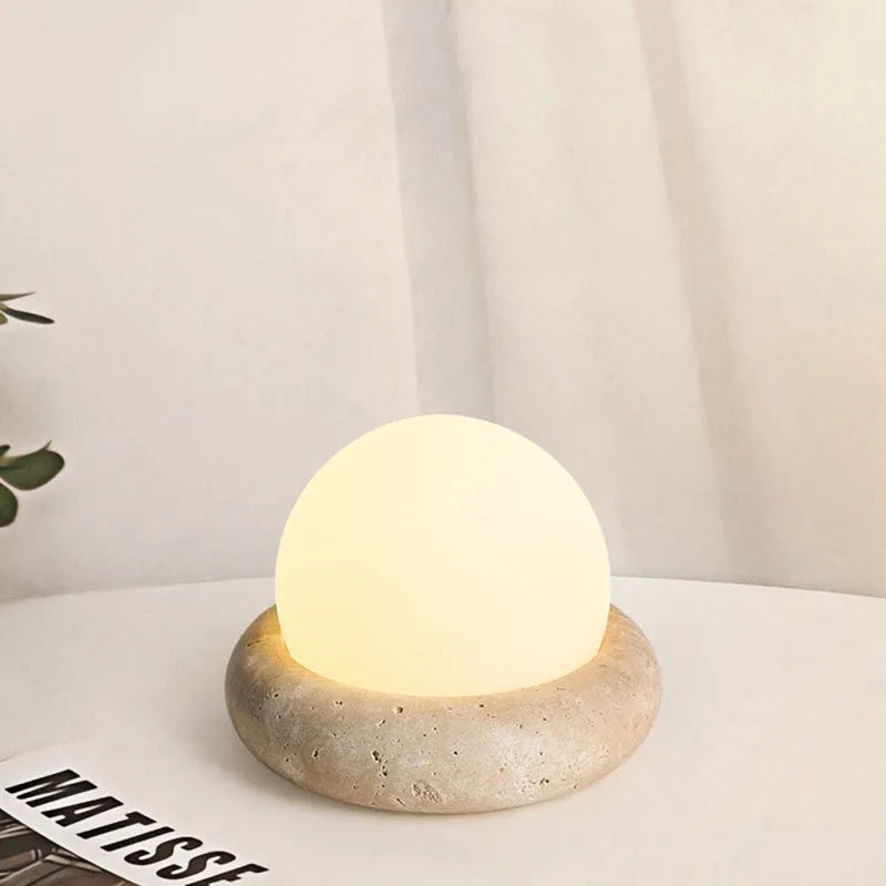 Cream-coloured modern bedside night light with remote control on a table.