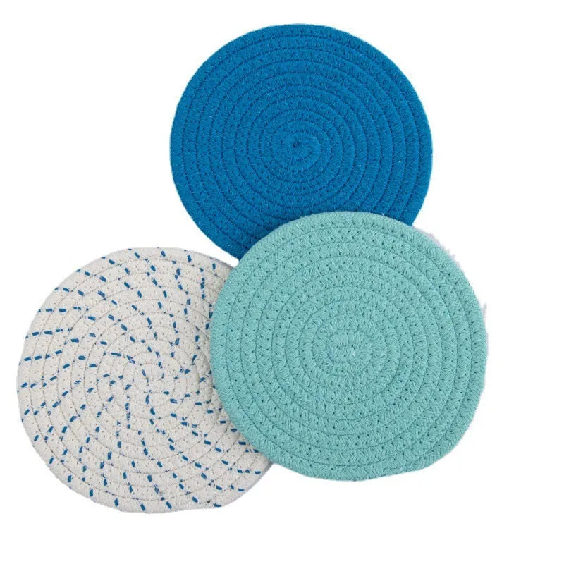 Set of three round cotton cord coasters in blue colour, 18cm diameter, on a table.