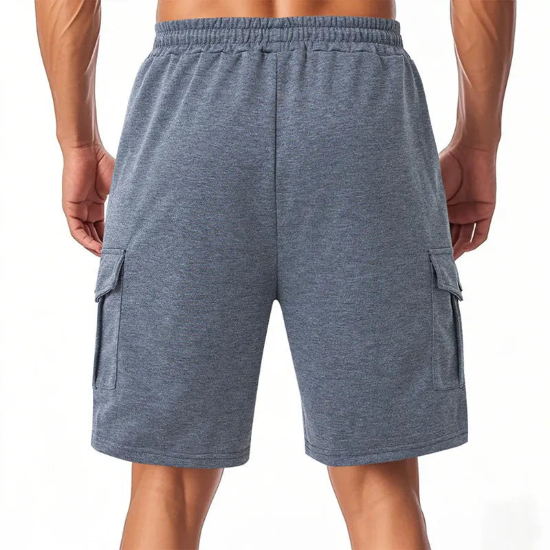 Man wearing light grey loose-fit cargo shorts made from textured towel fabric with multiple pockets.