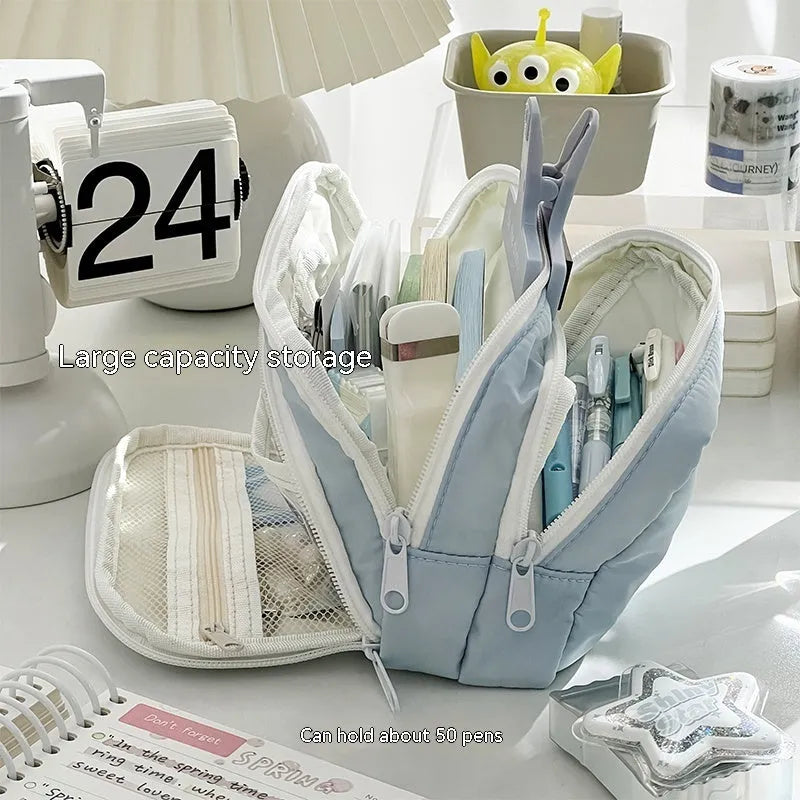 Double layer zippered pencil case in blue with a gift handle, shown next to pens and pencils.
