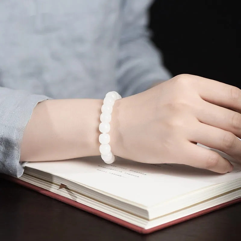 White Hetian jade barrel bead bracelet for men and women on a neutral background.