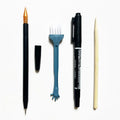 Scratch art pen tool kit with scraper, repair solution, brush, and bamboo stick on a craft table