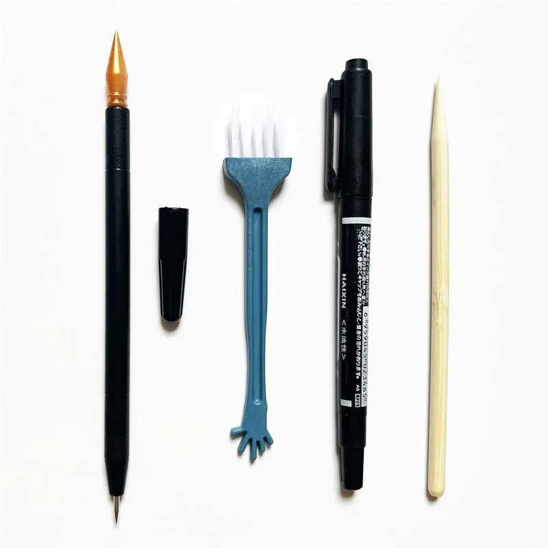 Scratch art pen tool kit with scraper, repair solution, brush, and bamboo stick on a craft table