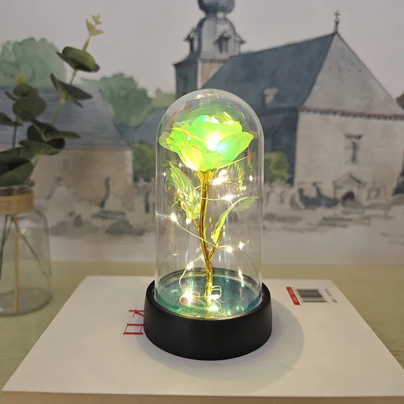Small glass night lamp with plastic flowers on a black base.