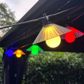 Outdoor LED string lights with flower-shaped bulbs hanging in a garden setting.