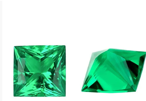 Cultivated emerald loose gemstones in round and fancy cut shapes on a dark background.