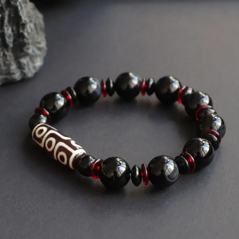 Hand-woven black agate dzi bead bracelet with 11mm geometric beads on a wrist.