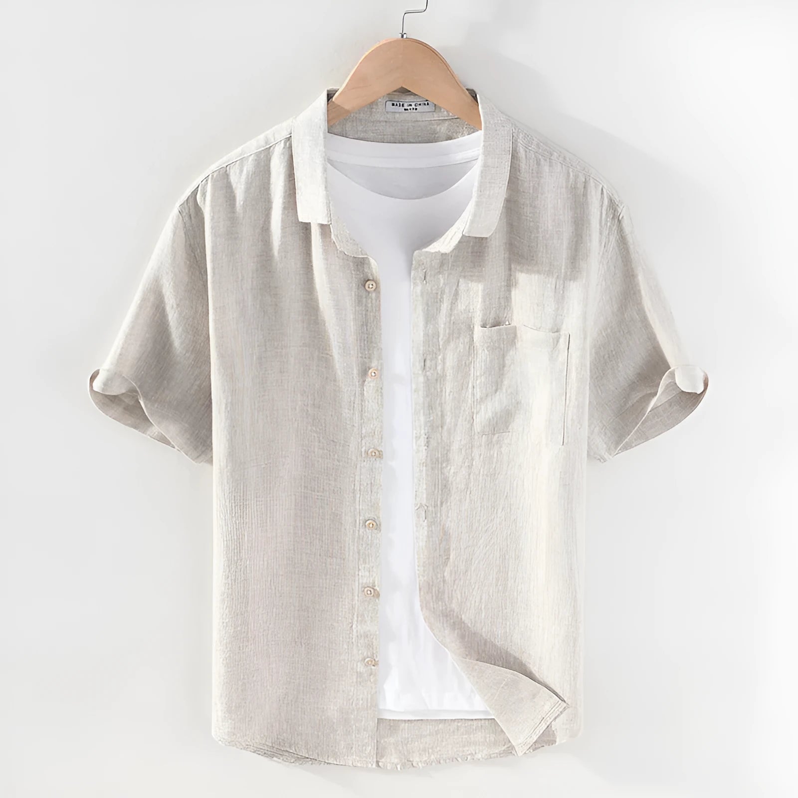 Men's raw jute coloured linen shirt with square collar and short sleeves on a hanger.