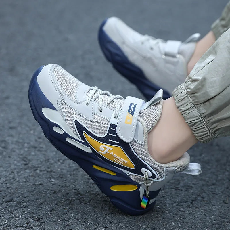 Boys' blue and black platform sports running shoes with Velcro straps on a hard ground surface.