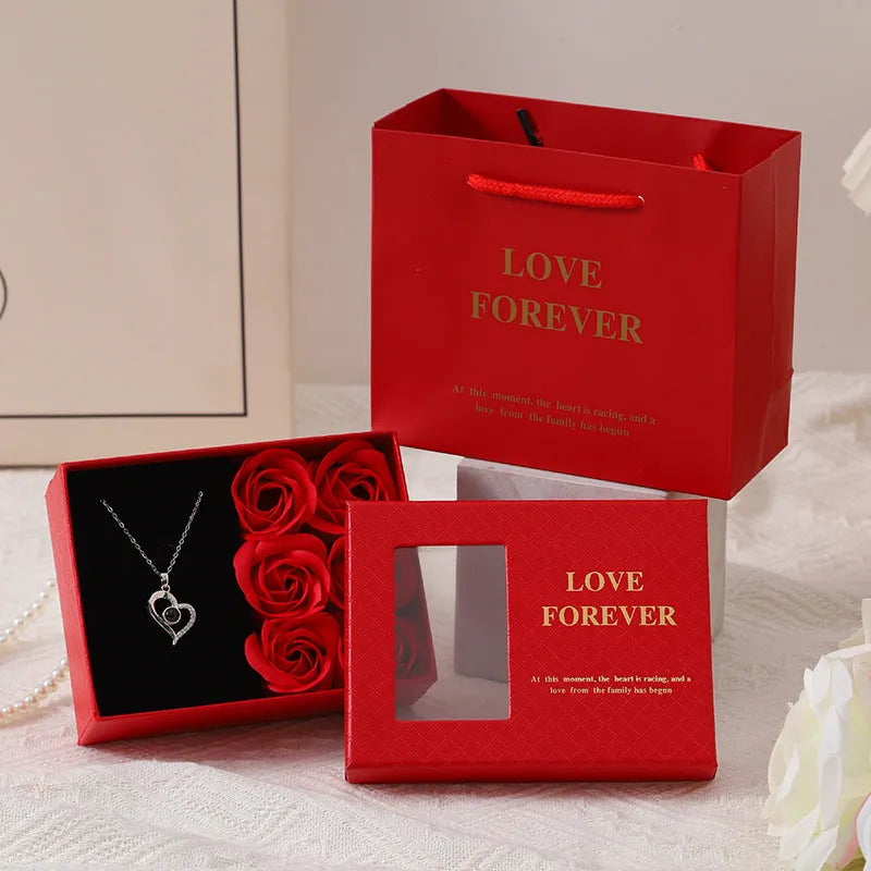 Korean style gift box open to show six red soap flowers, with a handbag beside it.