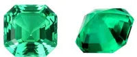 Cultivated emerald loose gemstones in round and fancy cut shapes on a dark background.