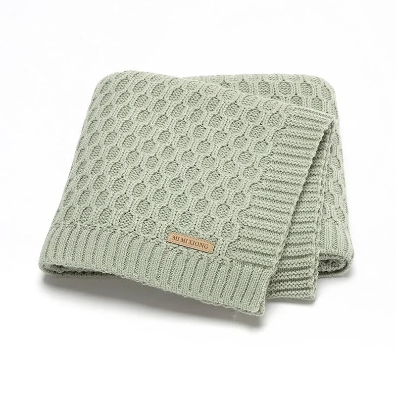Infant hug blanket with three-dimensional lines pattern in a solid colour, measuring 70 by 90 centimetres.