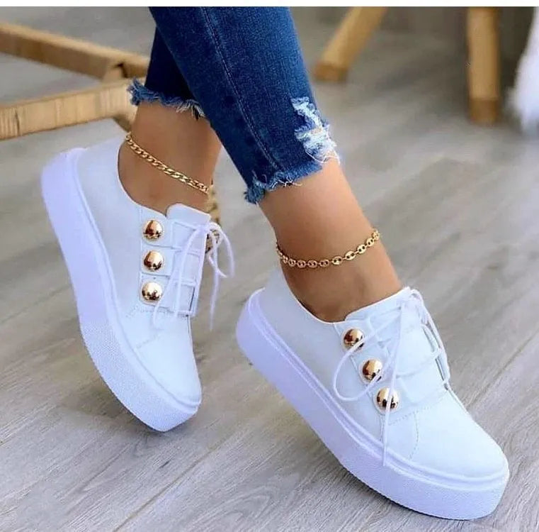Women's white lace-up flat sneakers with silver rivet details on the round toe.