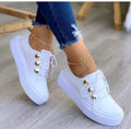 Women's white lace-up flat sneakers with silver rivet details on the round toe.