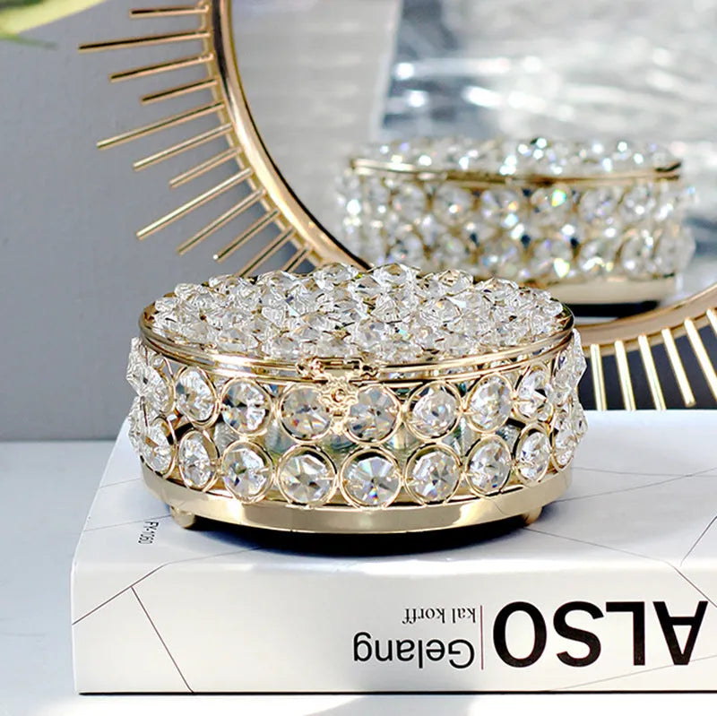 Transparent crystal glass jewelry box with a French gold metal frame on a table.
