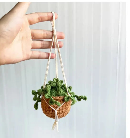 Green and white knitted wool car plant decoration basket with white hanging cord.