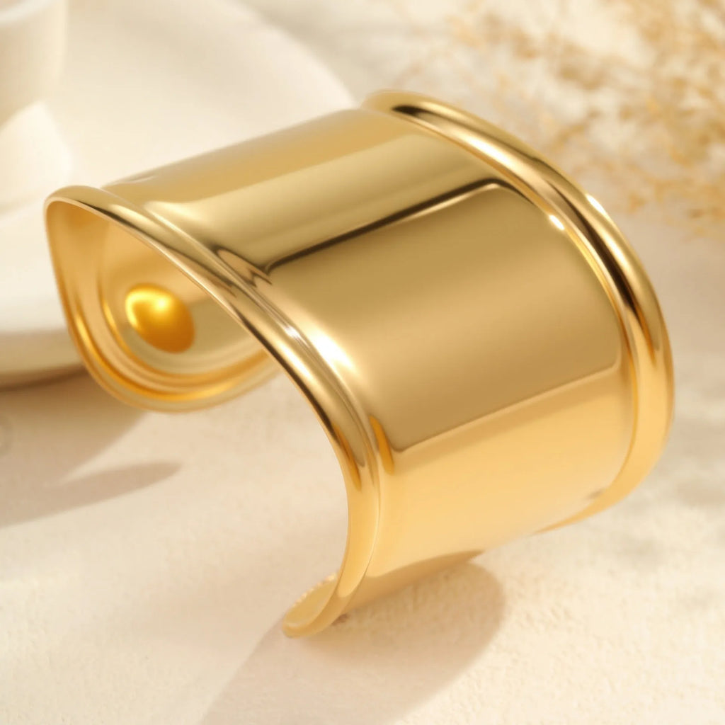 Women's stainless steel bracelet with 18K gold plating featuring geometric wave design and exaggerated wide band