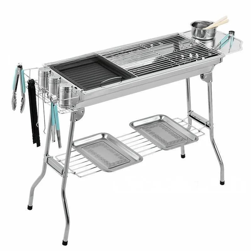 Large stainless steel folding barbecue grill with black cooking grate, shown outdoors.