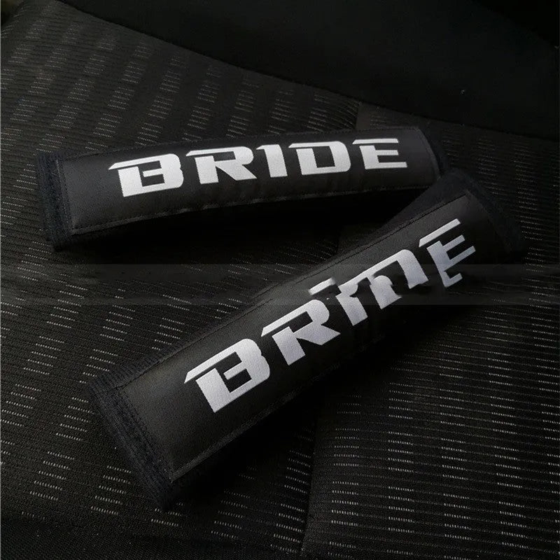 Pair of black car seat belt shoulder pads made from cotton sponge cloth, showing embroidery detail.