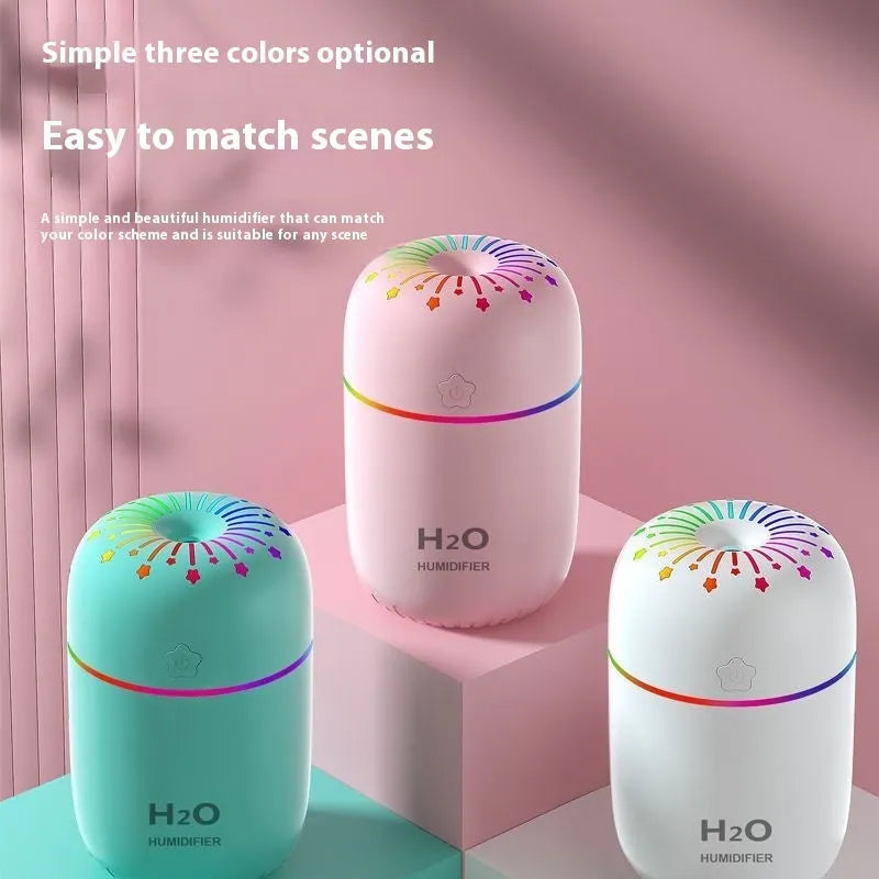 Small white USB-powered mini humidifier with water tank on a desk next to a laptop.