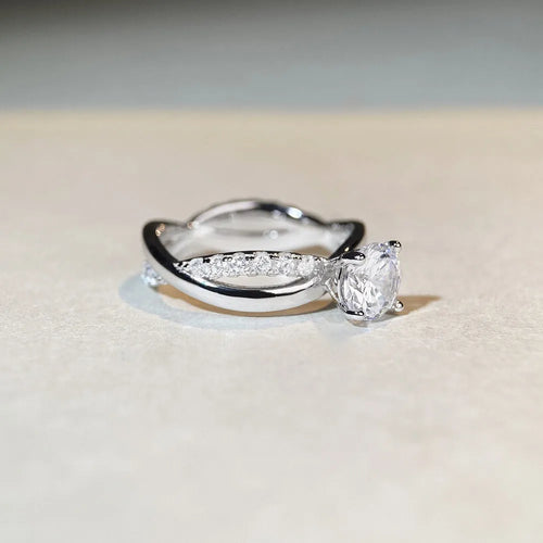 Close-up of a twisted sterling silver band moissanite ring with a four-claw setting and geometric lines.