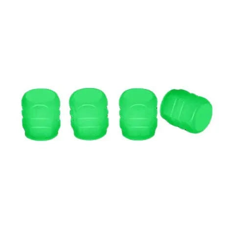 Set of luminous green rubber tyre valve caps on a car wheel valve stem, glowing in low light.
