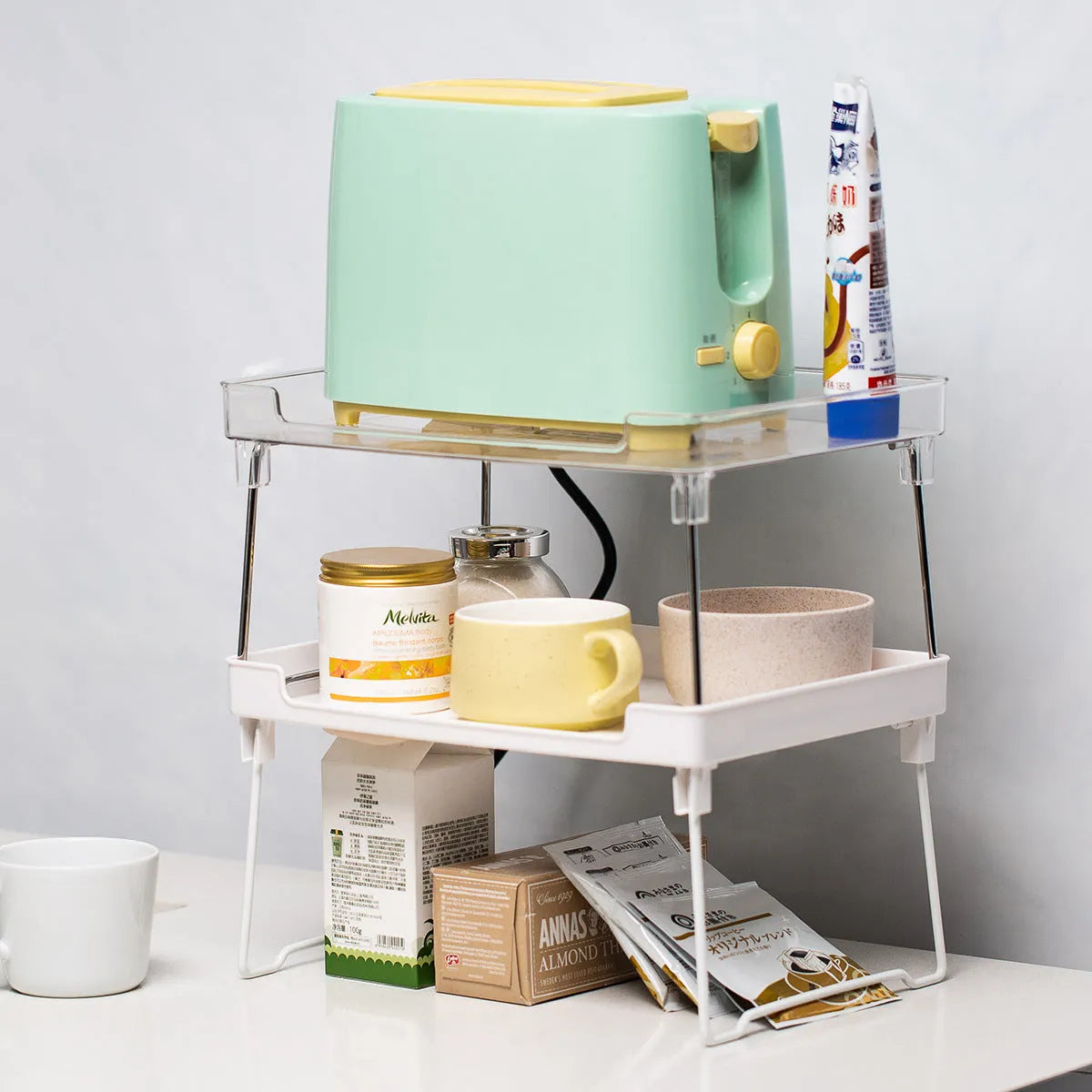 White and transparent plastic kitchen shelf organiser for countertop or cupboard storage.